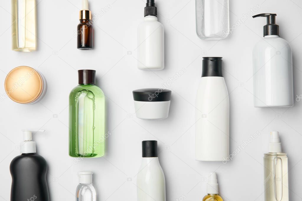 Top view of different cosmetic bottles and container on white background