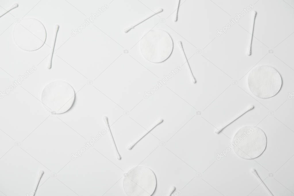 Top view of cosmetic pads and cotton sticks on white background