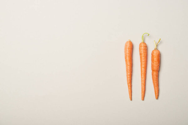 Top view of fresh carrots on grey background