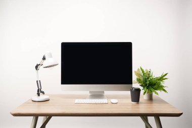 workplace with coffee to go, lamp, green plant and desktop computer with copy space isolated on white clipart