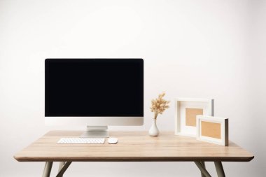 workplace with photo frames, dry flowers and desktop computer with copy space isolated on white clipart