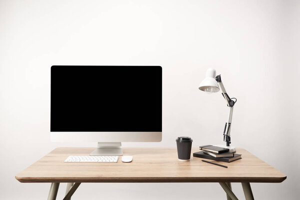 workplace with lamp, coffee to go, notebooks and desktop computer with copy space isolated on white