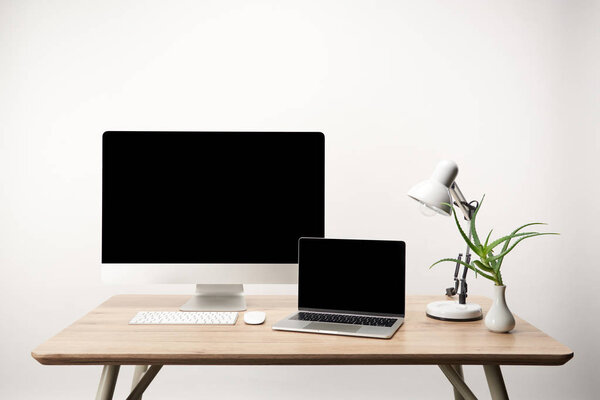 workplace with lamp, desktop computer and laptop with copy space isolated on white