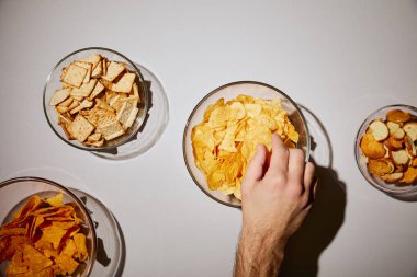 cropped view of man taking snack from glass bowl on white background clipart