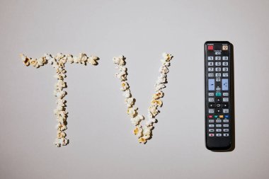 Beyaz arka plan üzerinde uzaktan kumanda ile tv yazı ile lezzetli patlamış mısır üstten görünüm