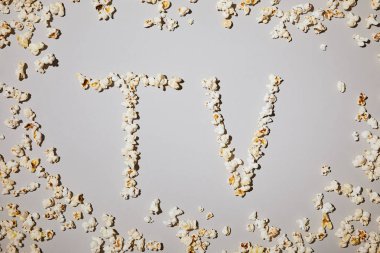 top view of of tasty popcorn with tv lettering isolated on white  clipart