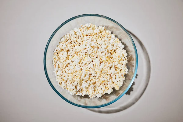 top view of tasty popcorn in bowl on white background