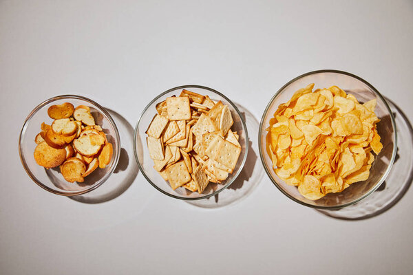 top view of salty snacks in glass bowl on white background