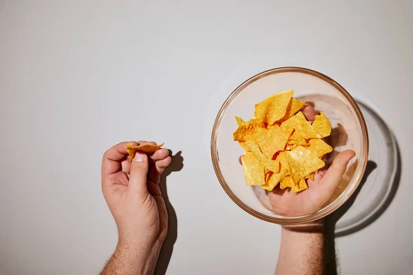 Cropped view of man holding snack near glass bottle with chips on white background — Stock Image Cropped View Man Holding Snack Glass Bottle Chips White Background Royalty Free Stock Images