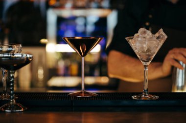 selective focus of alcoholic cocktails on counter with barman on background clipart