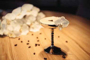 seçici odak metal cam ahşap masa üzerinde orkide çiçek ile dekore edilmiş alkollü kokteyl