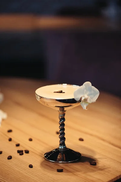 在木桌上用兰花装饰的金属玻璃中的酒精鸡尾酒的选择性焦点 — 图库照片