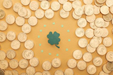 top view of golden coins with dollar signs and circle of shamrocks isolated on orange, st patrick day concept clipart