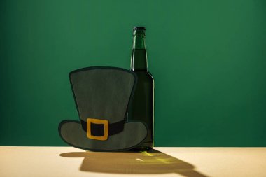 beer bottles and paper hat isolated on green, st patrick day concept clipart