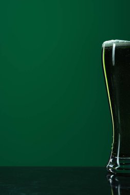 glass of beer with foam isolated on green with copy space, st patrick day concept clipart