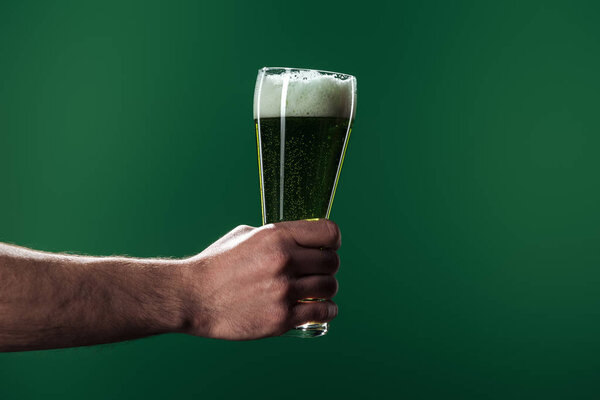 частичное представление человека, держащего бокалы пива с пеной, изолированной на зеленой концепции дня Святого Патрика
