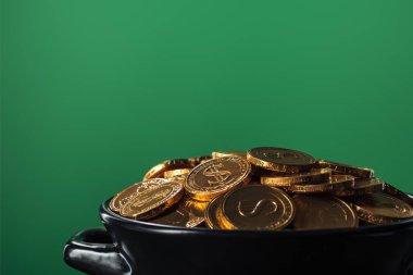 golden coins in black pot pot isolated on green with copy space, st patrick day concept clipart