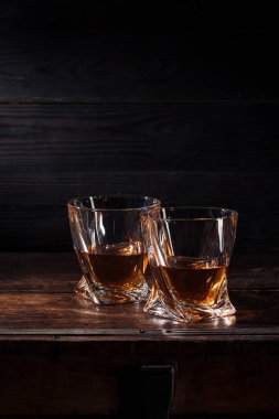 two glasses of whiskey on brown wooden table  clipart