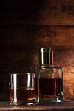 close-up view of glass of brandy and bottle on wooden table    clipart
