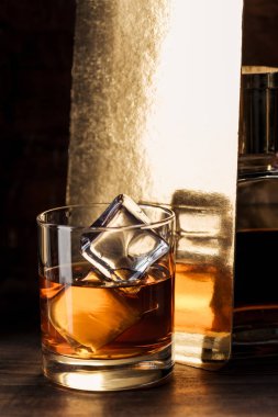 buz küpleri ile amber alkol cam ahşap masa üzerinde görmek