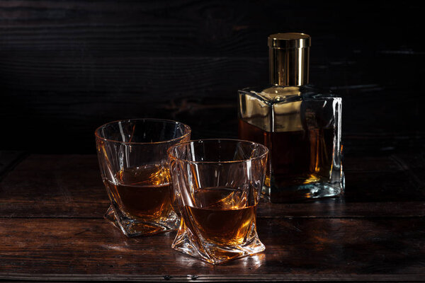бутылка и стаканы виски на коричневом деревянном столе
