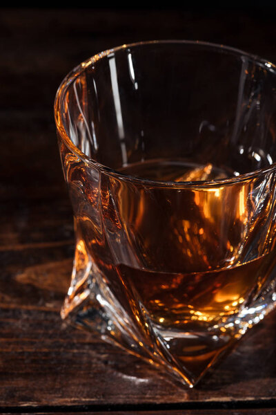 close-up view of amber alcohol in glass on wooden table