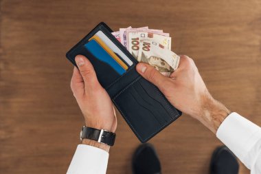 adamın hryvnyas banknotlar ahşap arka plan üzerinde kredi kartları ile cüzdan koyarak üstten görünüm
