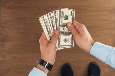bir dolarlık banknot ahşap arka plan üzerinde tutan adam üstten görünüm