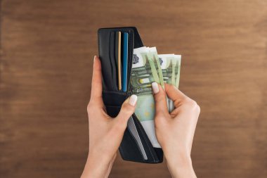Euro banknot m-cüzdana ahşap arka plan üzerine koyarak kadın üstten görünüm