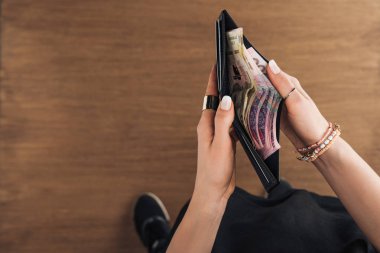 m-cüzdan hryvnias banknotlar ile ahşap arka plan üzerinde tutan kadın üstten görünüm