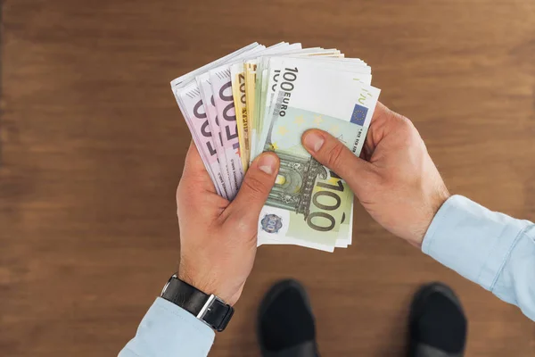 Vista Superior Del Hombre Sosteniendo Billetes Euros Sobre Fondo Madera — Foto de Stock