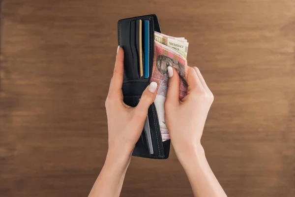 木製の背景を財布に Hryvnias 紙幣をかぶる女のトップ ビュー — ストック写真