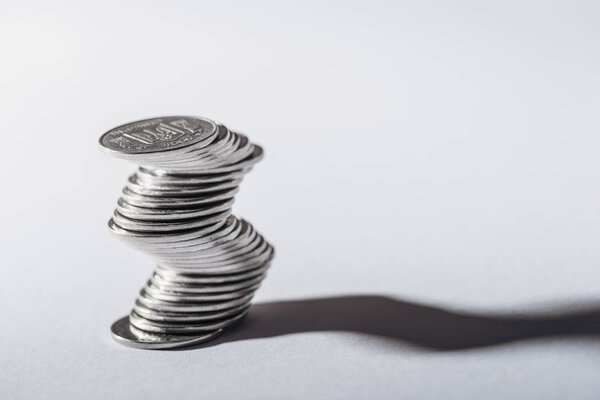 curved stack of ukrainian coins and shadow on grey background