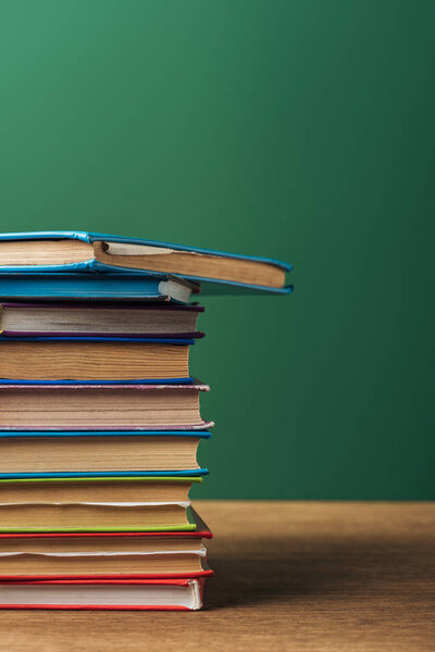  selective focus of stack with books on wooden table and green background