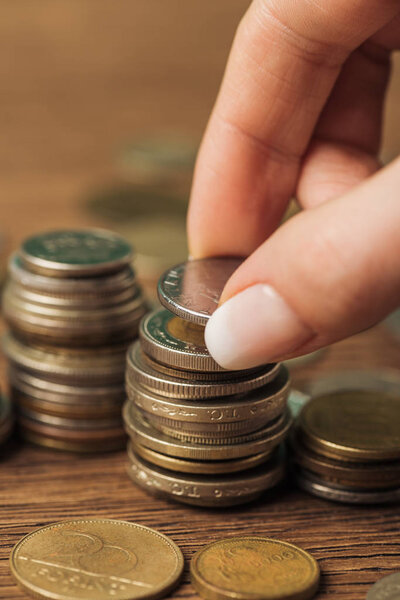 selective focus of woman putting coin on stack on wooden background