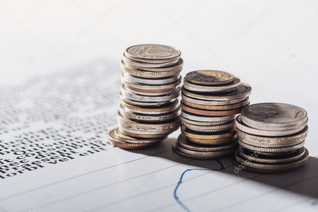 selective focus of coins stacks on document with graphs and blurred background