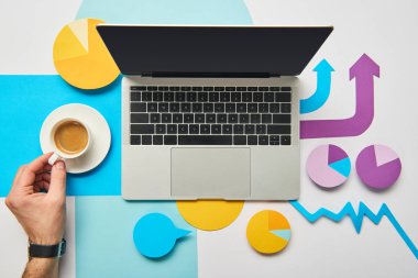 bir kahve fincanı laptop ve kağıt grafikler ve grafik, beyaz arka plan üzerinde işaretçiler yakın tutan adam üstten görünüm 