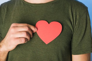 Yeşil t-shirt erkekte görünümünü kesilmiş kağıt kalp tutan