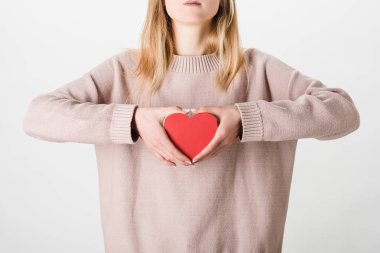 Partial view of woman in beige sweater holding paper heart on white background clipart