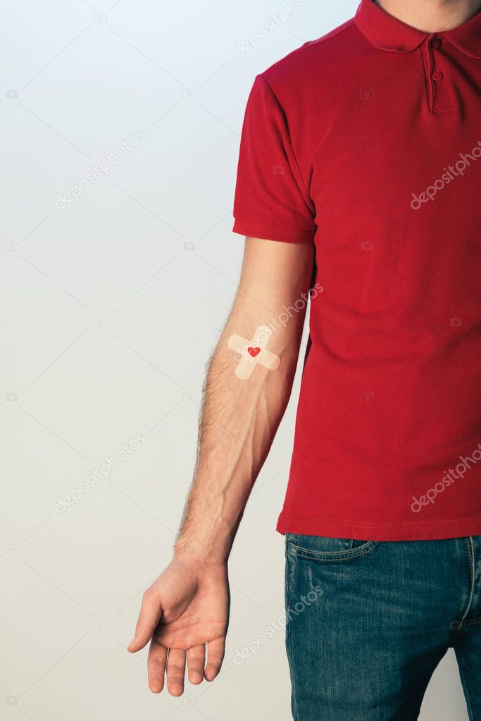 Partial view of patient in red t-shirt with plasters, blood donation concept