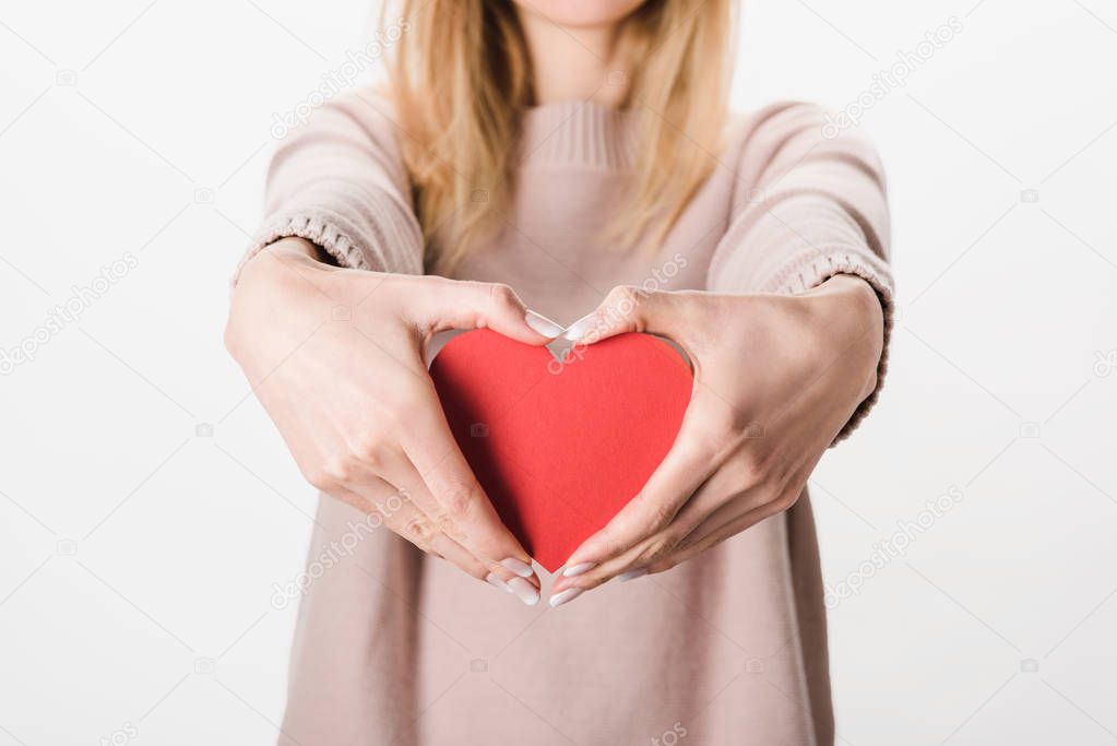 Partial view of blonde woman in beige sweater holding paper heart on white background
