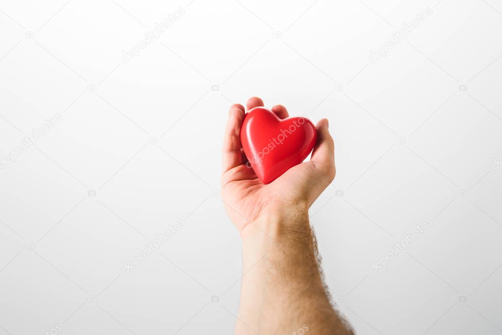 Partial view of man holding toy heart on grey background