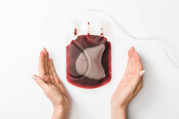 Cropped view of woman holding drip with blood on white background, blood donation concept