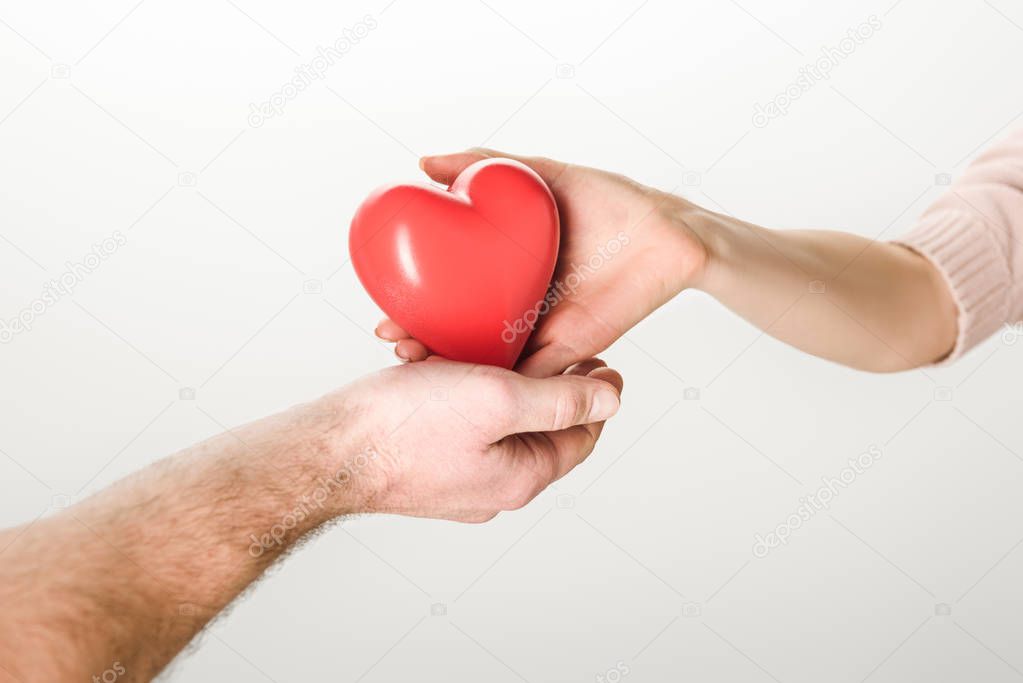 Partial view of man and woman holding toy heart on white background