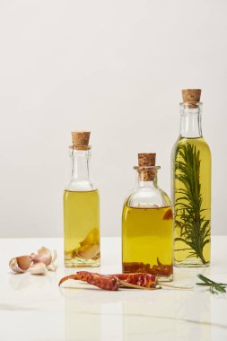 çeşitli baharatlar ve biberiye beyaz yüzeyi ile aromalı yağ ile farklı şişeler