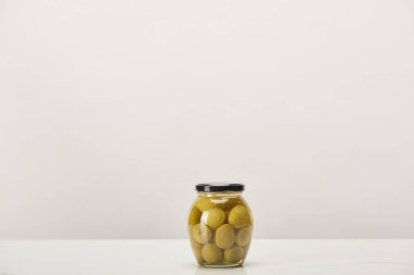 glass can of conserved olives on white surface clipart