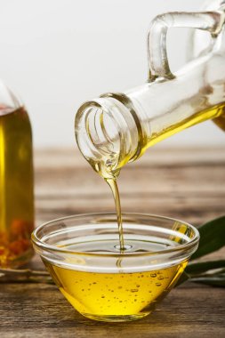 kahverengi ahşap yüzey üzerinde cam kaseye şişe yağ boşaltma