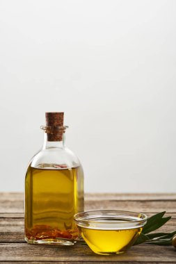 Zeytinyağı, zeytin ağacının yaprakları ve zeytin ahşap yüzeyde şişe ve cam kase