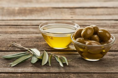 zeytin ve yağı ve zeytin ağacı dalı Ahşap yüzeyi ile cam kase