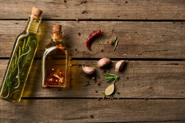 üstten görünüm farklı baharatlar ve ahşap yüzeyde biberiye aromalı yağ şişe